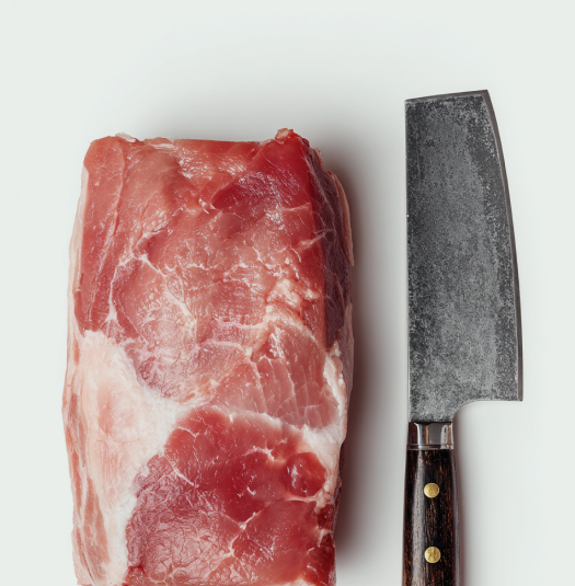 Cleaver and raw meat on a wooden board